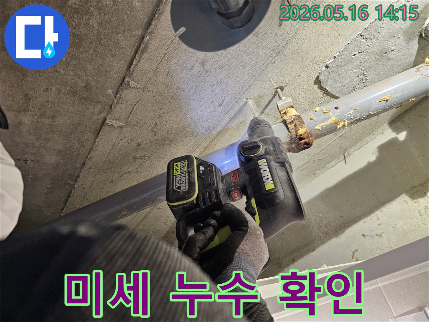 누수 엔지니어가 천장 배관 주변의 미세한 누수 지점을 확인하기 위해 드릴로 콘크리트를 타공하는 모습-정밀 진단을 위한 작업입니다.