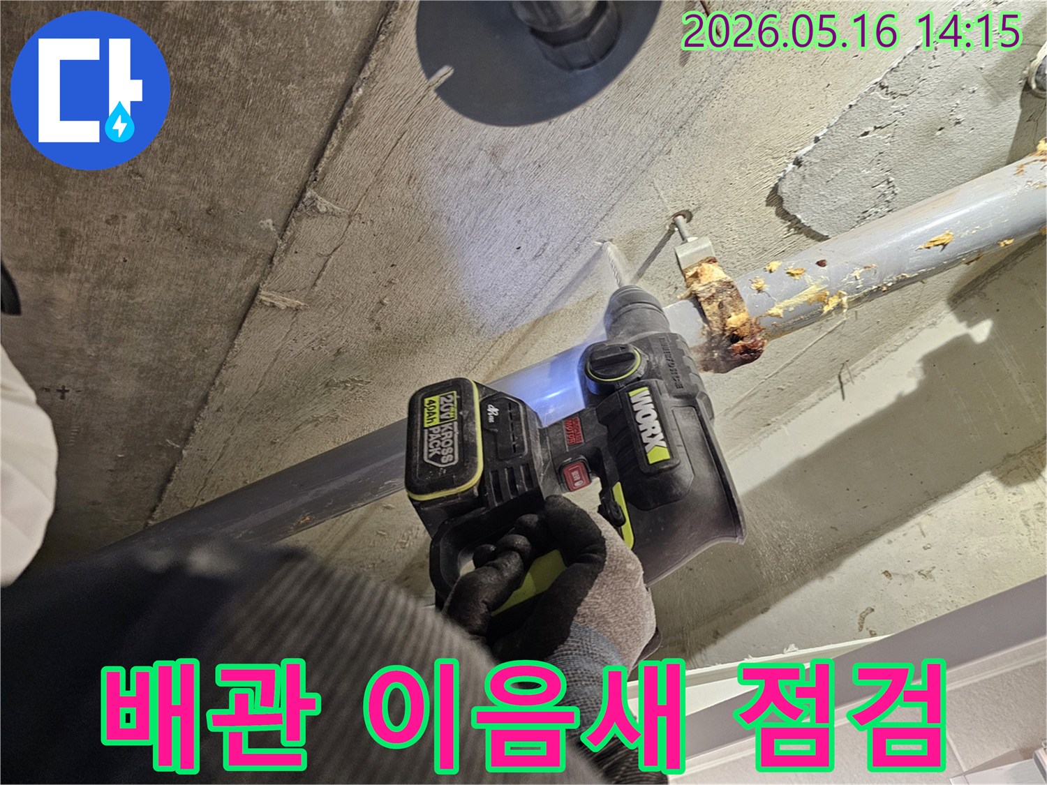 누수 전문가가 천장 배관 이음새의 누수 여부를 확인하기 위해 드릴로 콘크리트를 타공하는 모습-정확한 누수 진단을 위한 작업입니다.