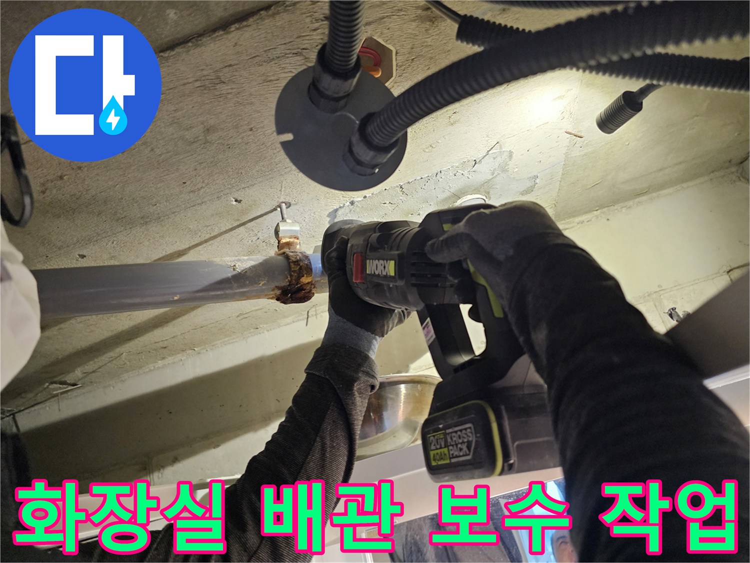 전동 드릴을 사용하여-오수관 연결 부위의 클램프를 조이는 작업 중인 모습