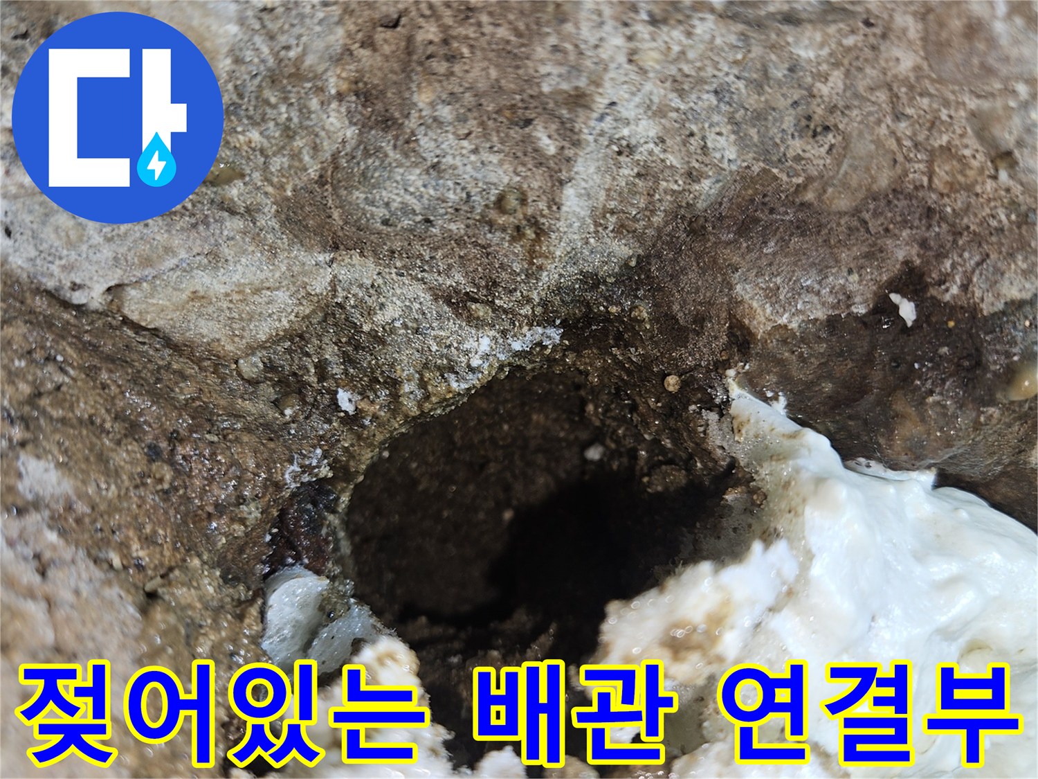 배관 주변의 젖은 벽면과 하얀색 석회질 같은 퇴적물을 근접 촬영한 사진입니다.