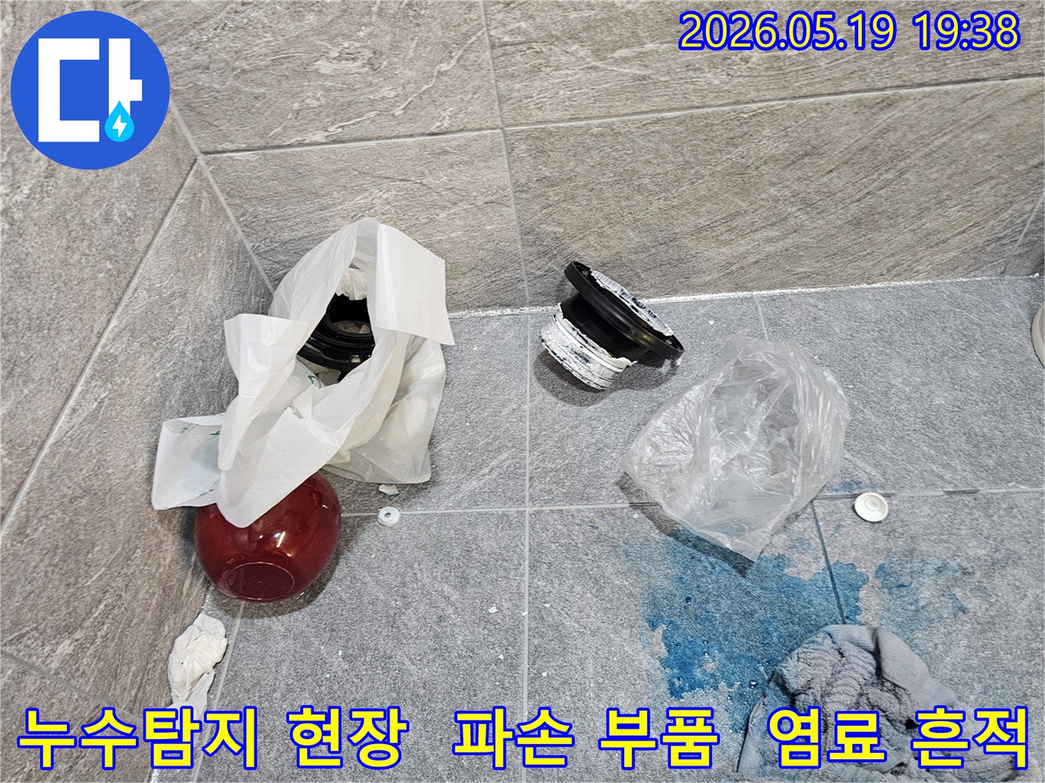 누수 탐지 현장에서-파란색 염료로 확인된 누수 지점과-교체를 기다리는 손상된 배관 부품들이 바닥에 있습니다