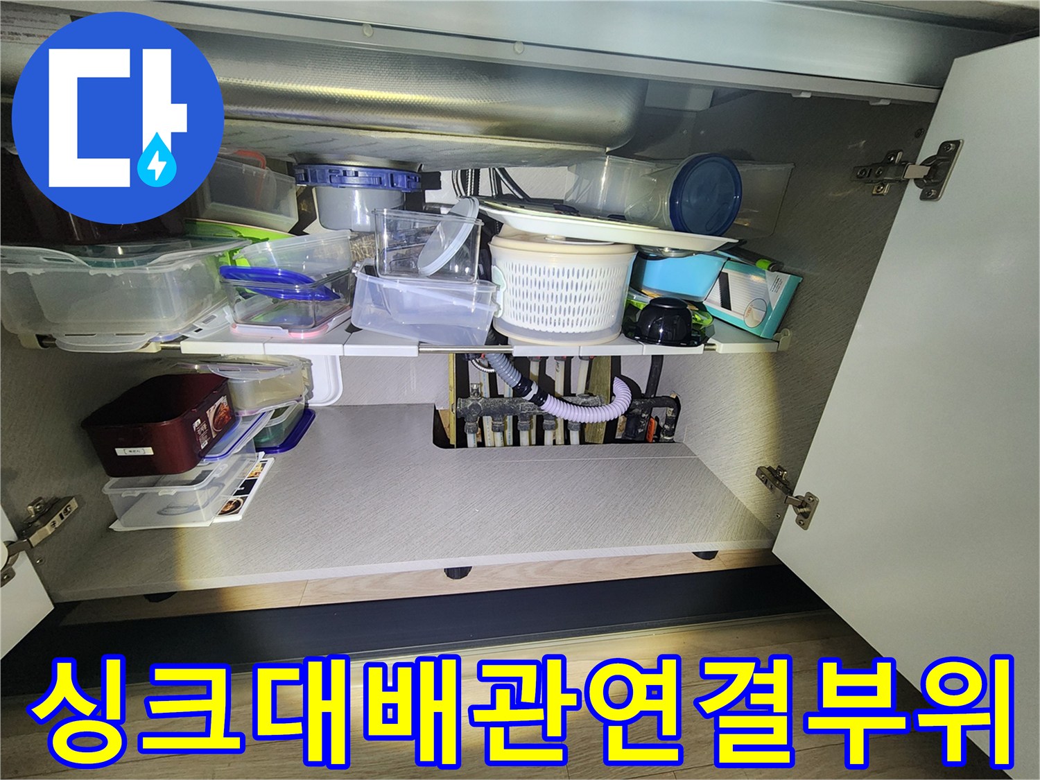 싱크대 아래 수납장 내부의 분배기와 하수 배관 모습