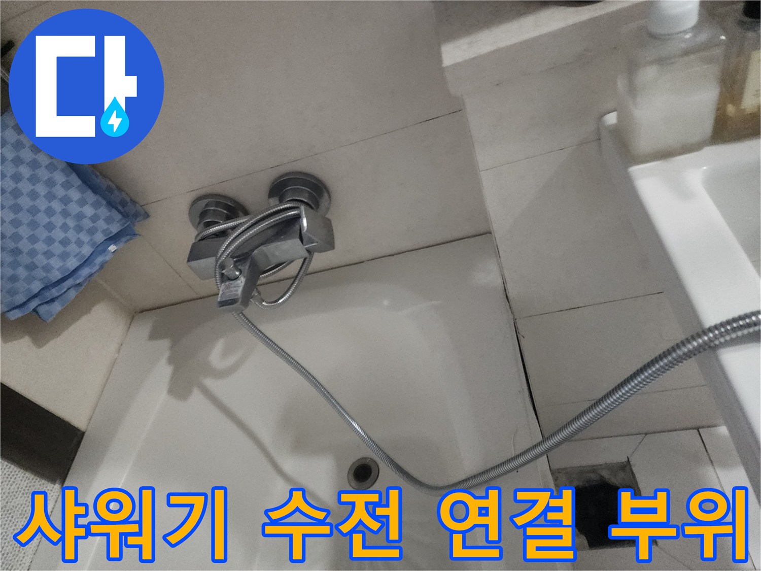 욕실 벽면에 설치된 샤워기 수전과 호스의 접합 상태를 보여줍니다.