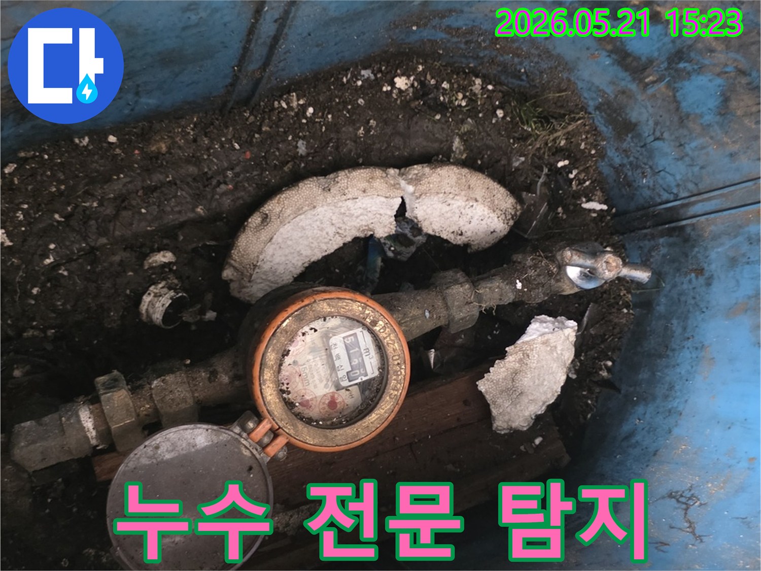 오래된-수도계량기와-주변의-오염된 환경 속에서-누수 지점을-정확히-탐지하는-전문가의-모습