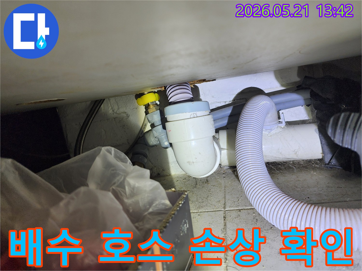 세탁실 배수 호스에 발생한 균열이나 손상으로 인한-누수 지점을 면밀히 확인하는 작업 현장입니다.