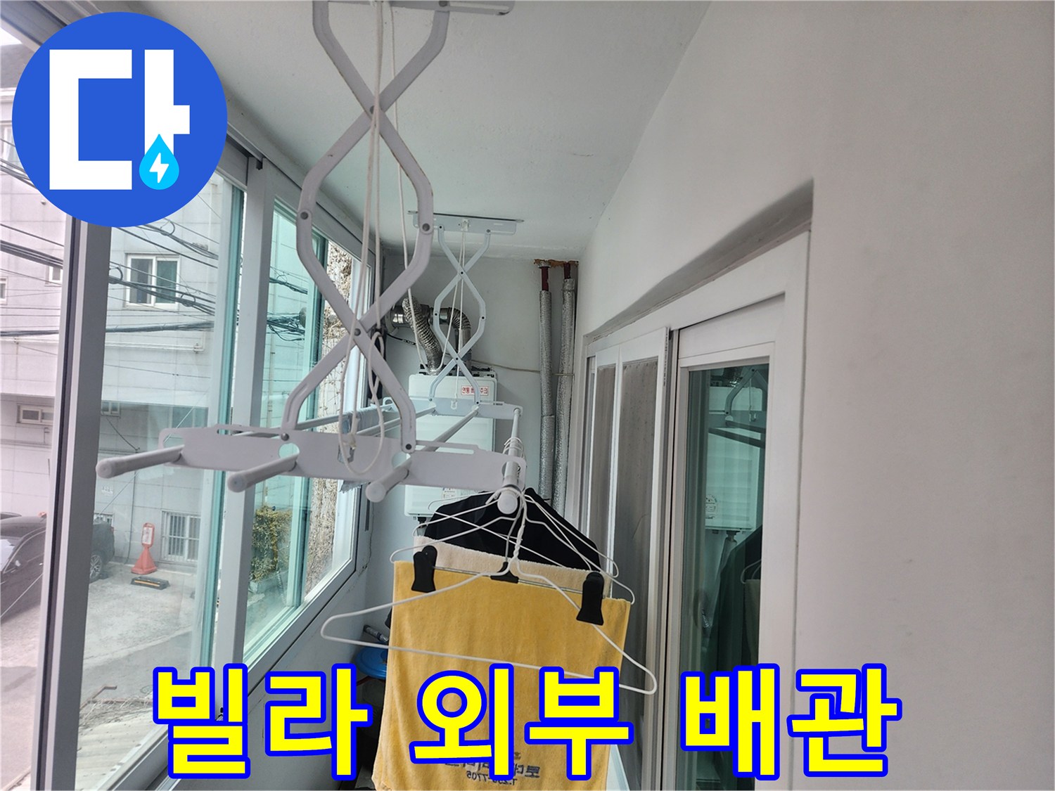 빌라 외벽 근처에 설치된 화이트 색상의 배관 지지대와 건조대 모습입니다.