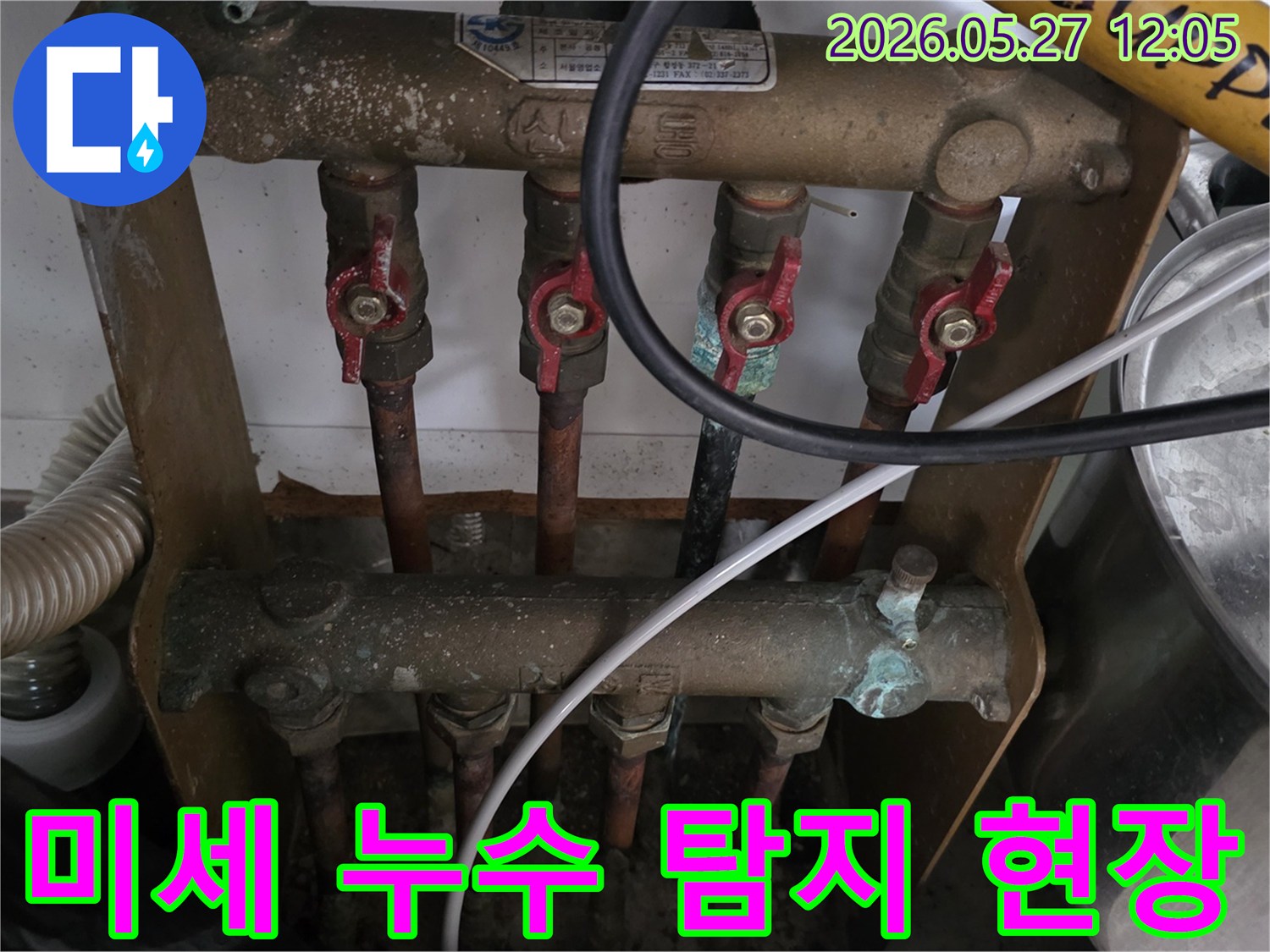 오래된 아파트의 보일러 분배기에서-발생한 미세 누수를-전문가가 정밀 탐지 장비로-확인하고 있는 모습입니다