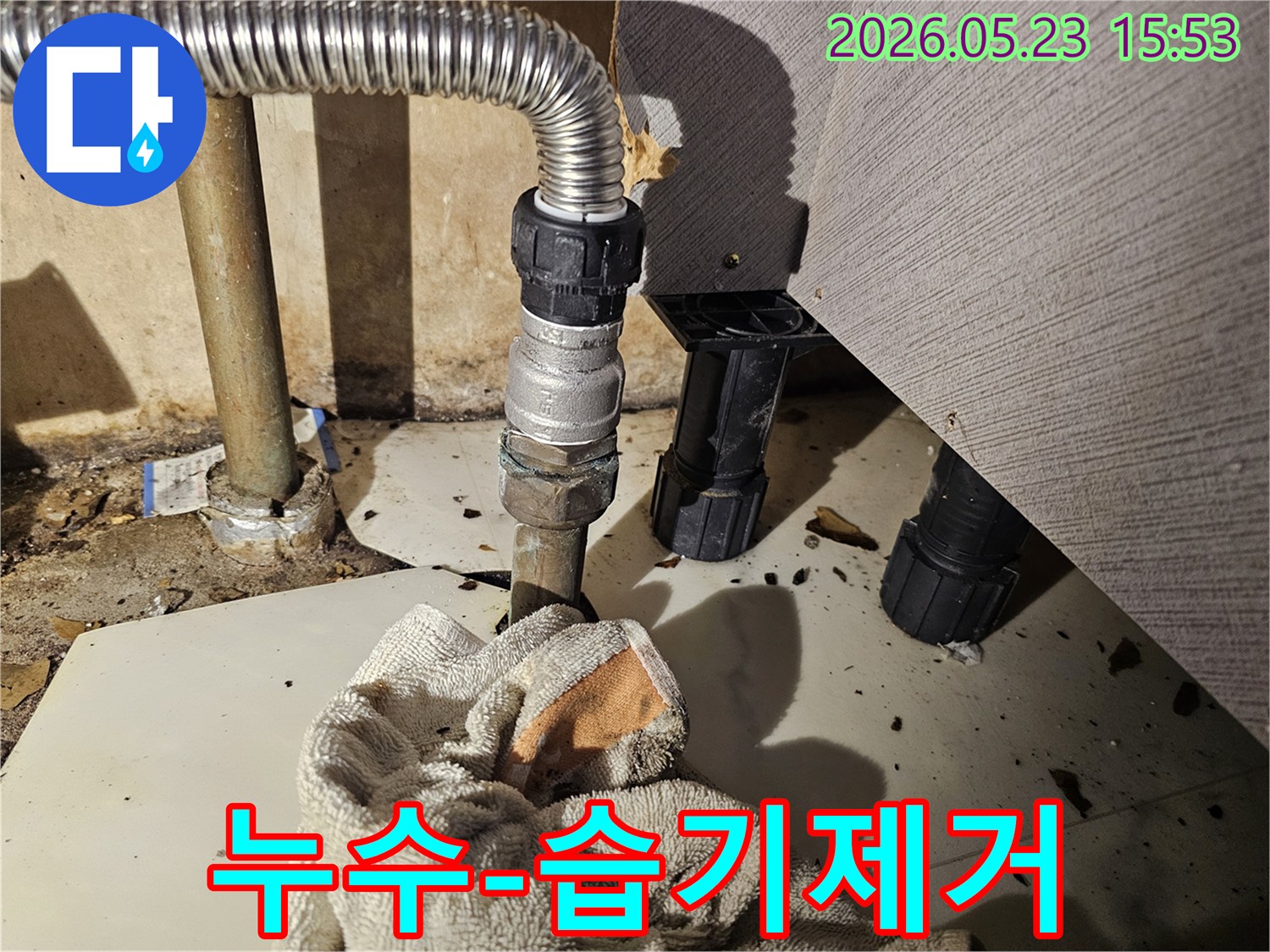 배관 연결부에서 물이 새어-바닥에 젖은 수건이 놓인-누수 습기 제거 현장