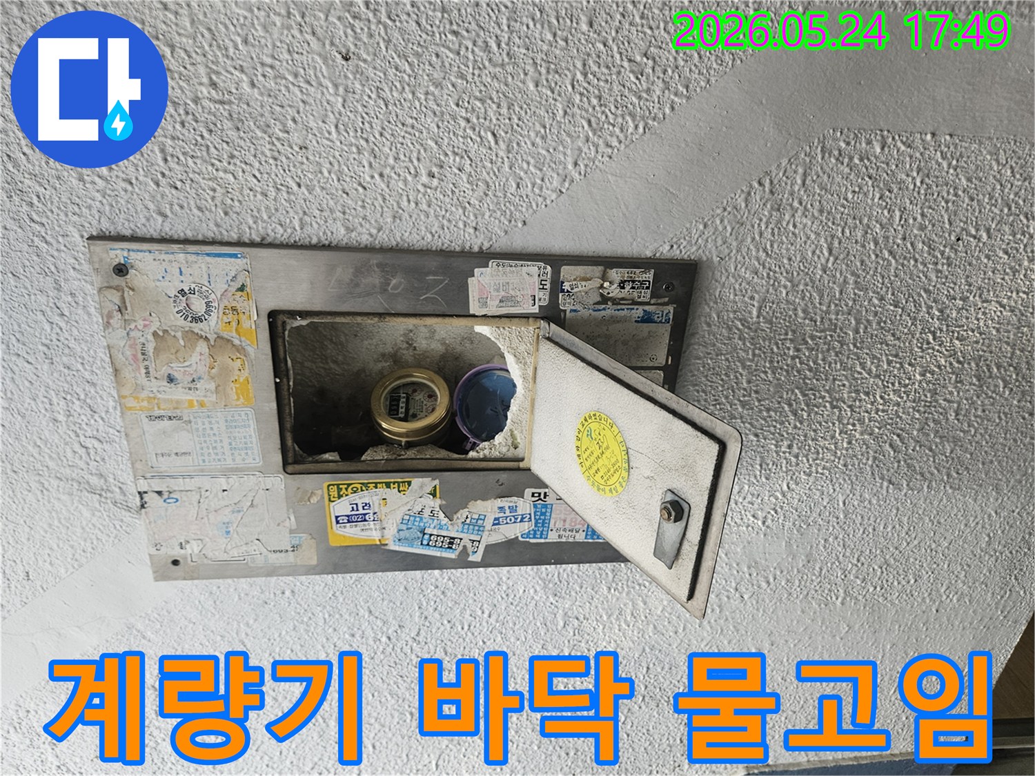 수도계량기함 바닥에 물이 고여있고-주변 벽면에도 물기가 스며든-누수 현장을 보여주는 사진입니다.