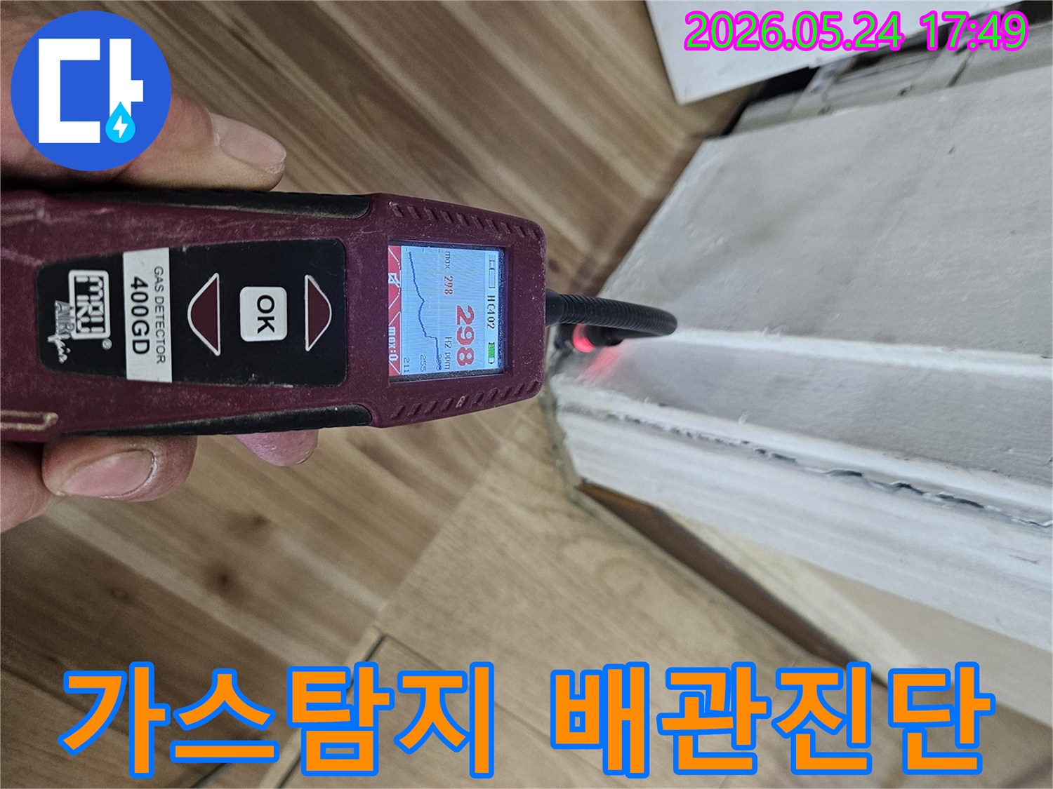 숙련된 누수 엔지니어가 가스 탐지기를 사용하여 벽면 하단에서 누수 반응을 면밀히 확인하고 있습니다.