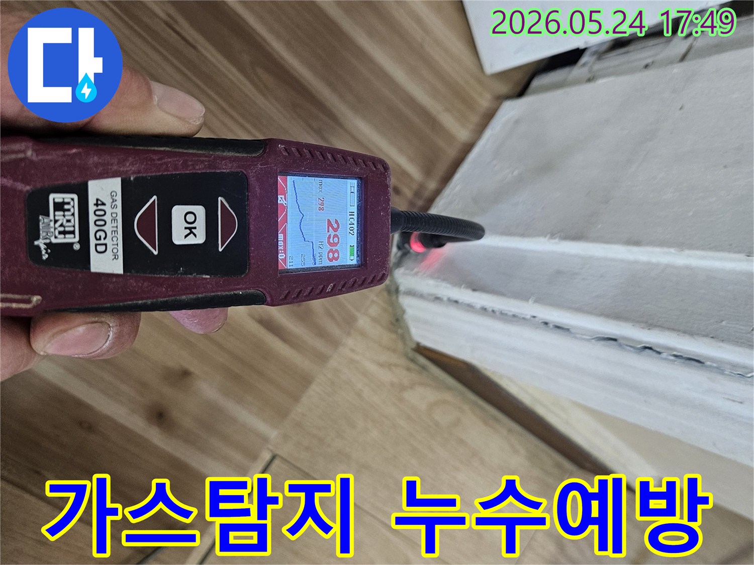숙련된 누수 엔지니어가 가스 탐지기를 사용하여 벽면 하단에서 누수 반응을 면밀히 확인하고 있습니다.