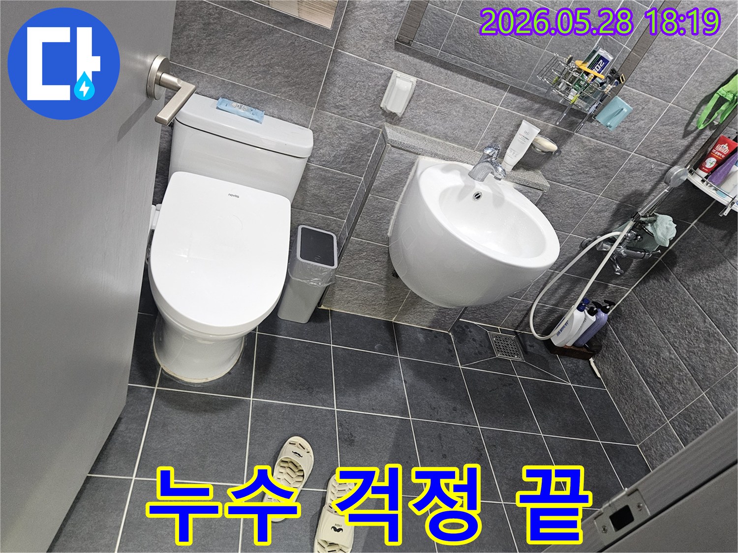회색 타일로 이루어진 욕실 내부-변기와 세면대-그리고 샤워 공간이 보이는-누수 점검 전의 깨끗한 모습입니다.