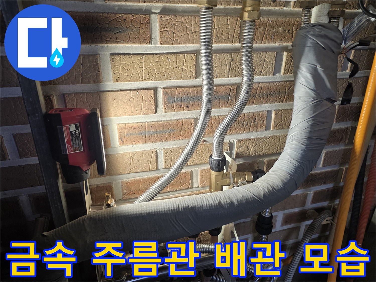 벽돌 벽면에 설치된 은색 주름관과 보온 배관의 상세 사진