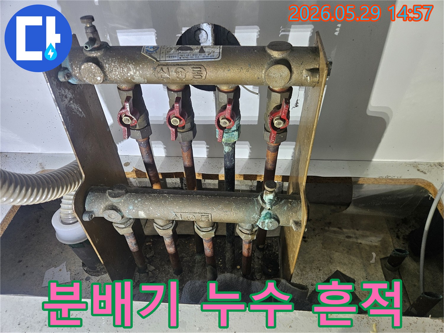 오래된 아파트의 난방 분배기에서-심각한 부식과 함께 누수 흔적이 발견되어-전문가가 교체 작업을 준비하고 있습니다.
