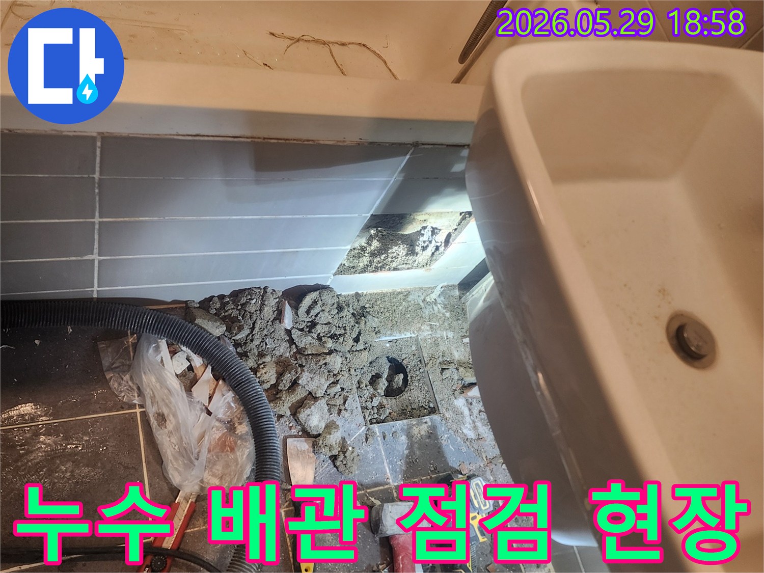 이 사진은-금호동 아파트 욕실에서-누수 발생으로 인해-바닥 타일을 제거하고-노출된 배관의 상태를-정밀하게 점검하는-작업 과정을 보여줍니다
