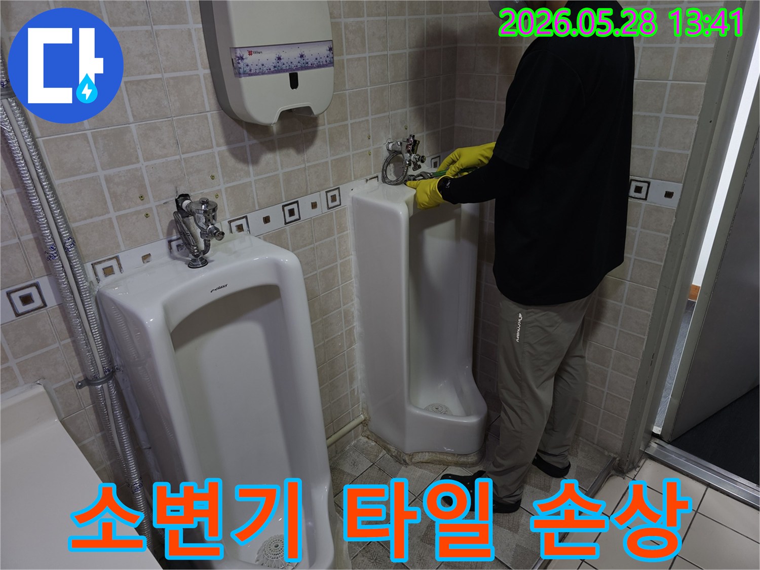 누수 전문가가-소변기 주변 타일의-손상 여부를 확인하며-누수 원인을 파악하고 있습니다