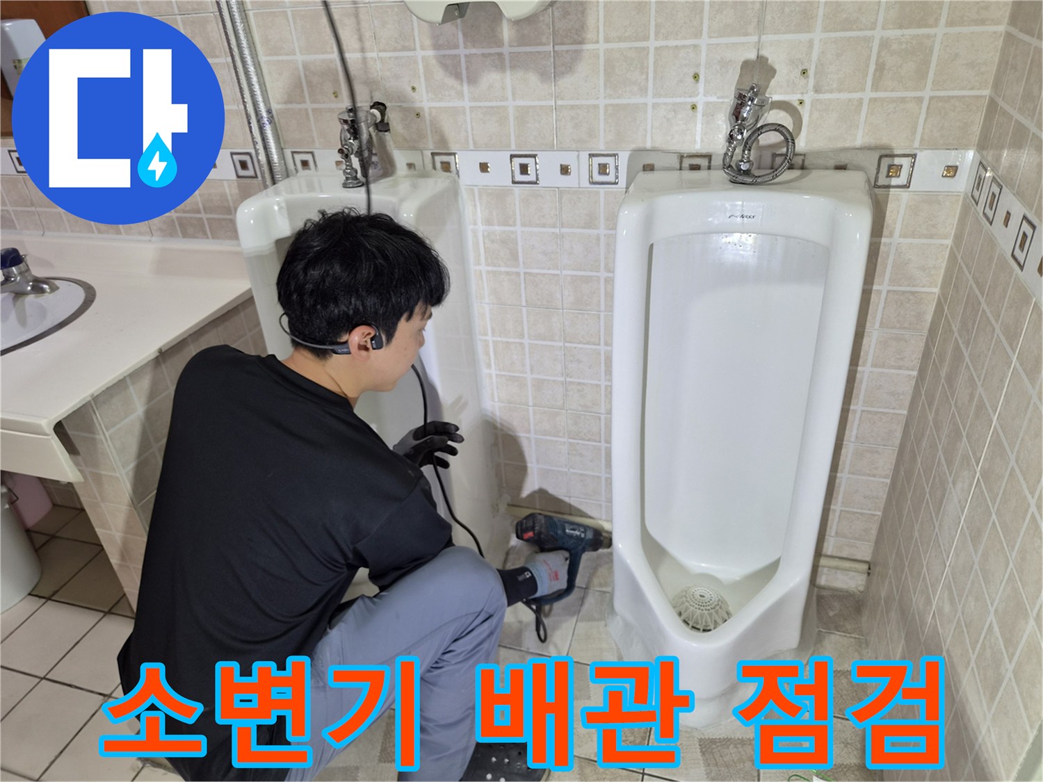 소변기 하단 부위의 배관 상태를 확인하기 위해 장비를 사용하는 모습