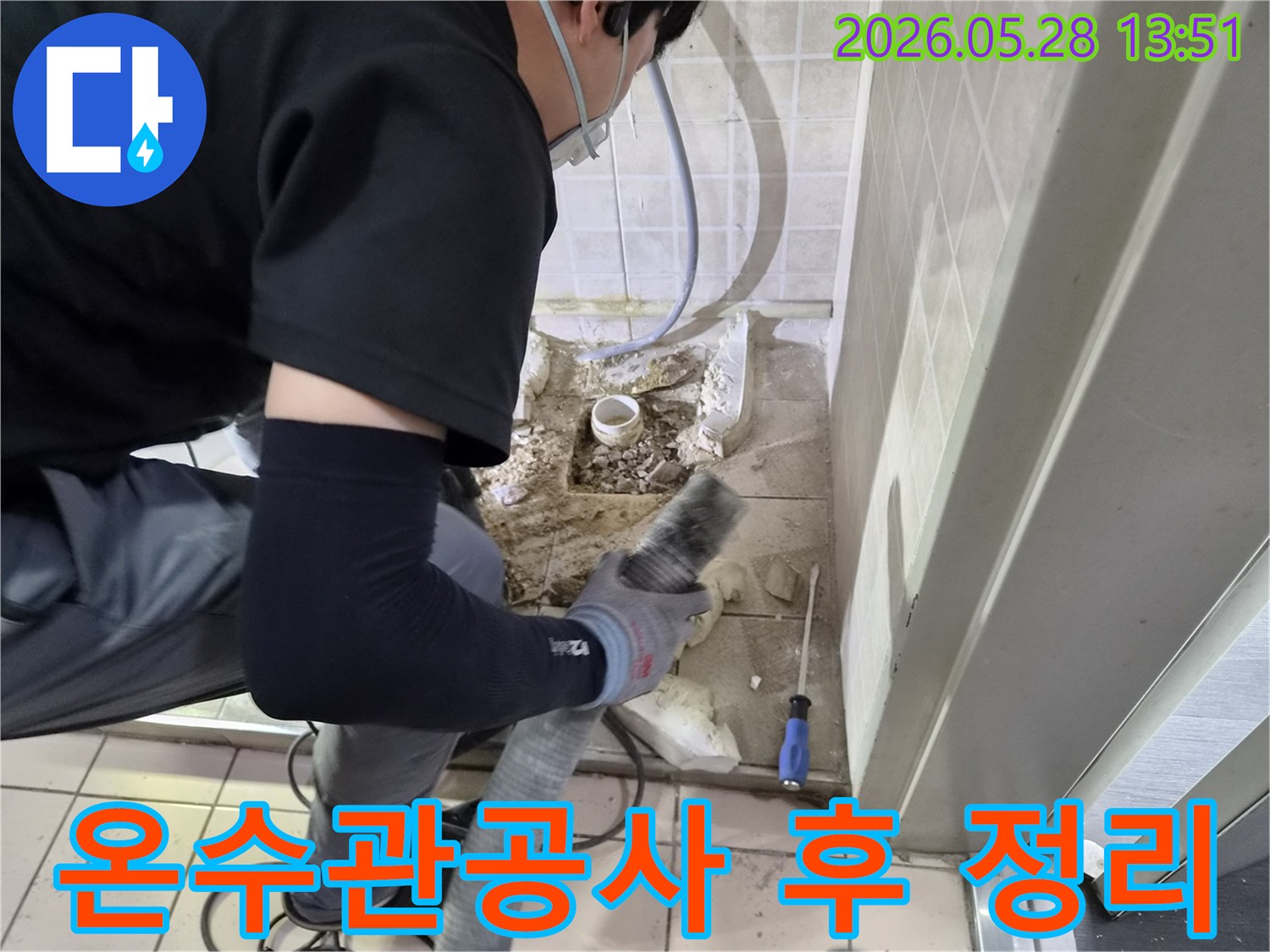 안전 마스크를 착용한 작업자가-온수관 누수 보수 후-바닥에 남은 파쇄 잔해물을-흡입기로 깨끗하게 청소하고 있습니다.