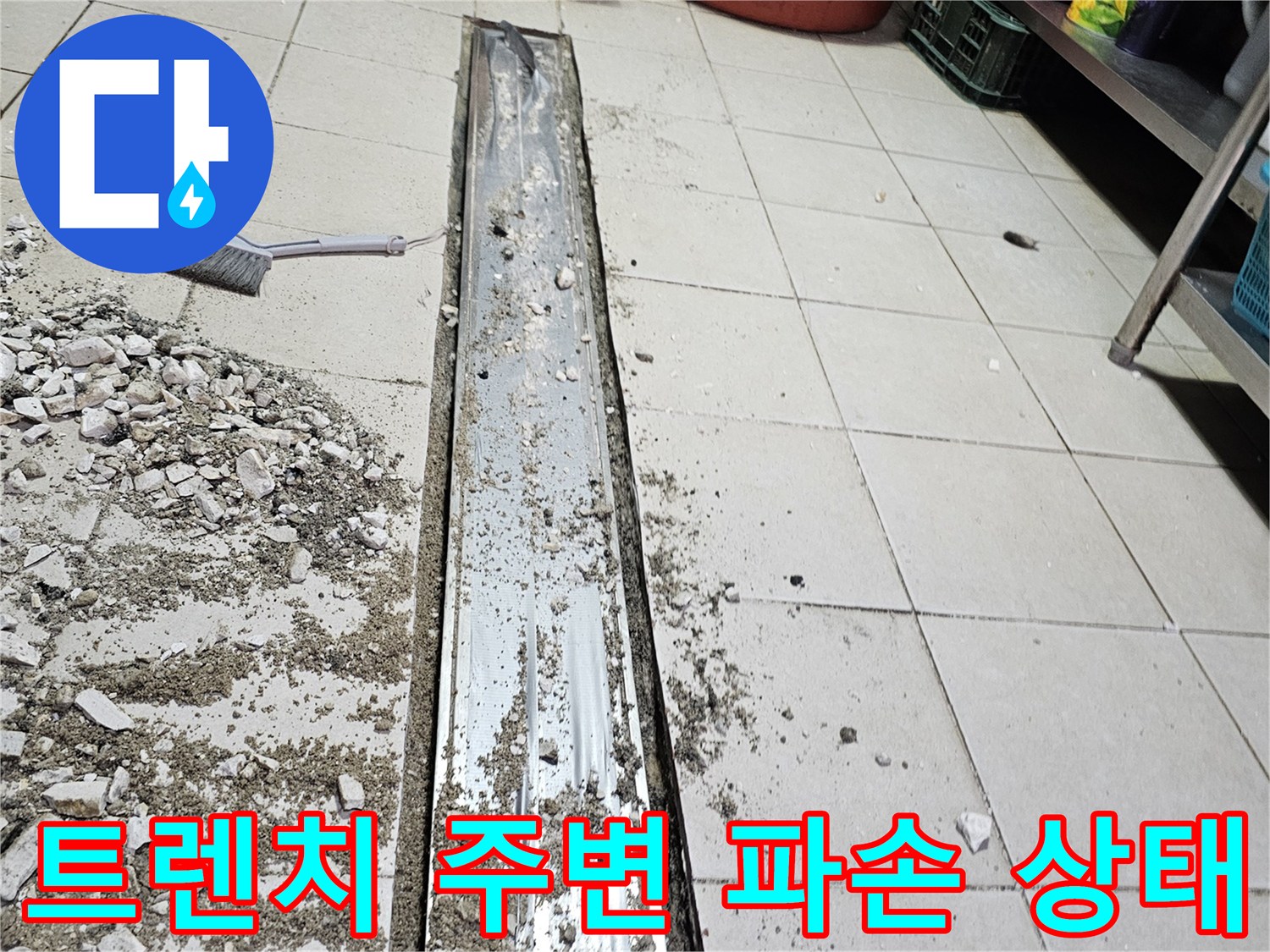 식당 주방의 금속 트렌치 주변 타일과 바tes가 파손된 모습