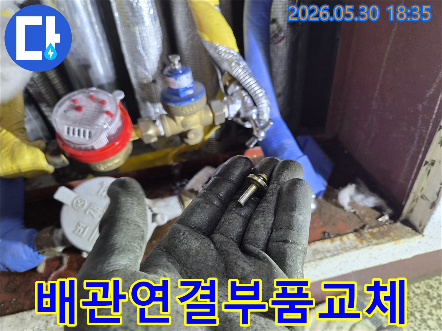 아파트-수도-배관-연결부에서-발견된-손상된-부품을-작업자가-교체하기-위해-들고-있는-장면