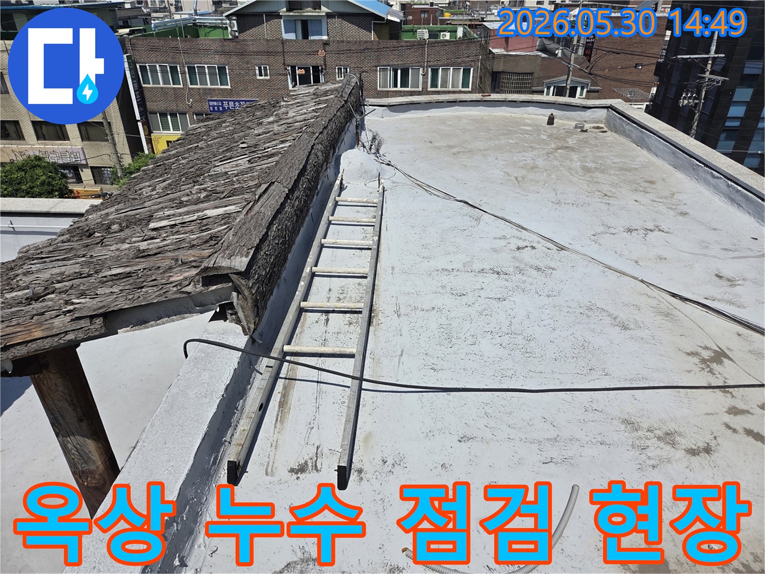 오래된 지붕과 평평한 옥상-그리고 누수 점검을 위한 사다리가 놓여있는-건물 옥상 현장 사진