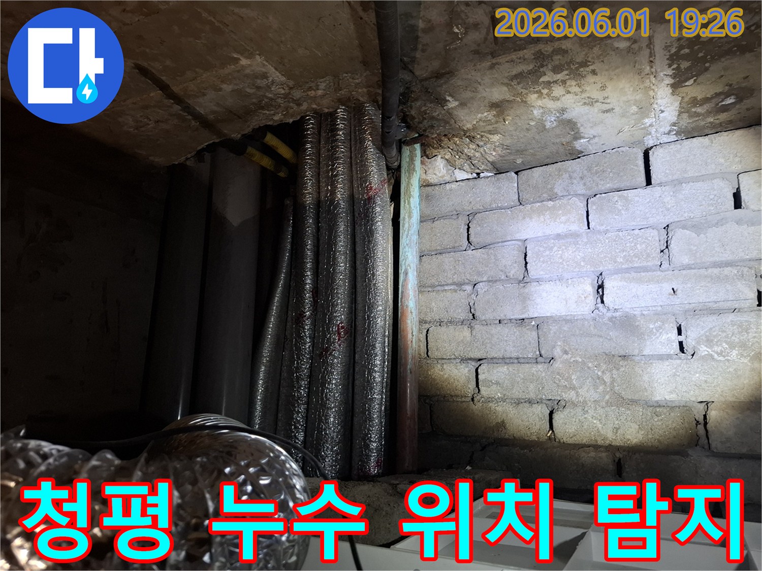 어두운 지하 공간에서-천장 배관과-벽돌 벽면의-누수 흔적을-확인하는 모습의-누수탐지 현장 사진입니다