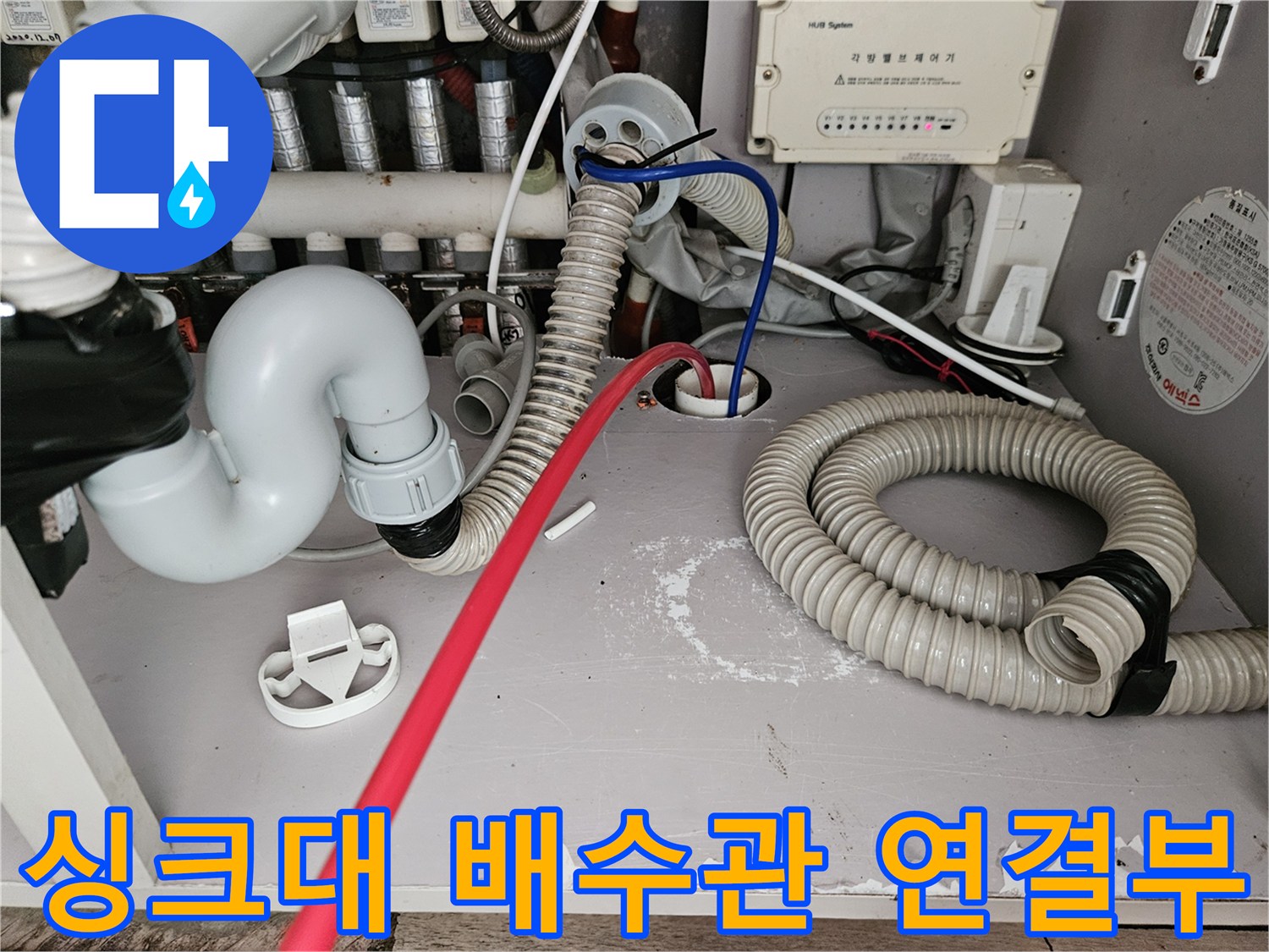싱크대 하부장 내부의 굴곡진 배수 호스 및 연결 부위