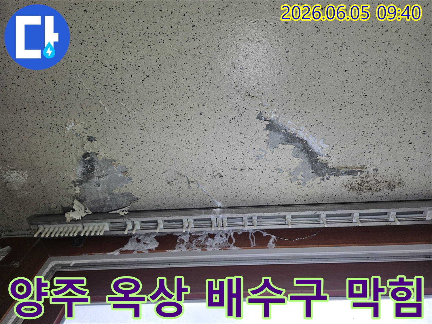 상가 내부 천장에 물이 새어 얼룩이 지고-물자국이 넓게 퍼진 모습으로-옥상 배수구 막힘으로 인한 빗물 역류 누수 피해를 보여줍니다.