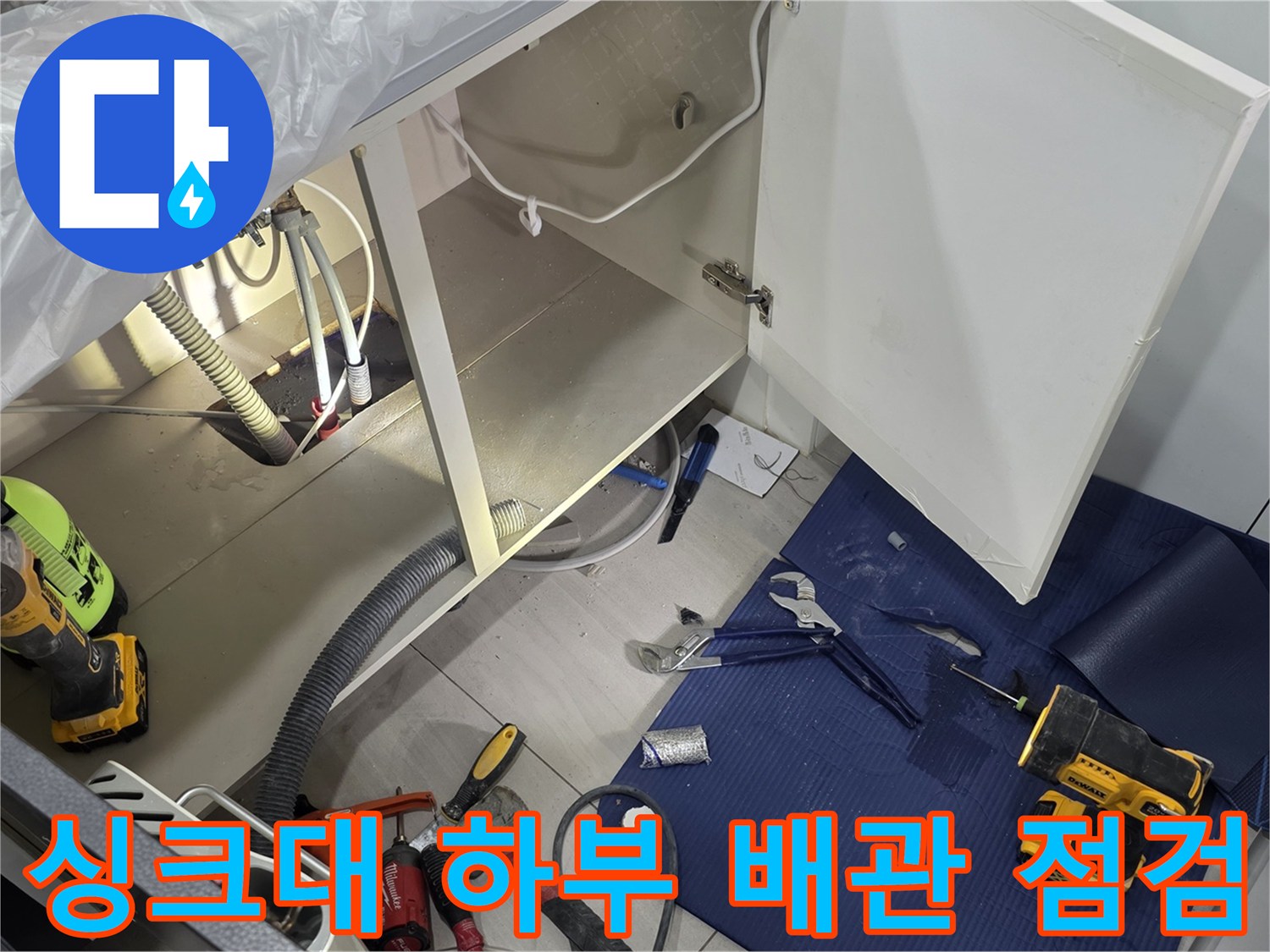 일산서구 주방 싱크대 하부장의 열린 문과 노출된 배관 상태