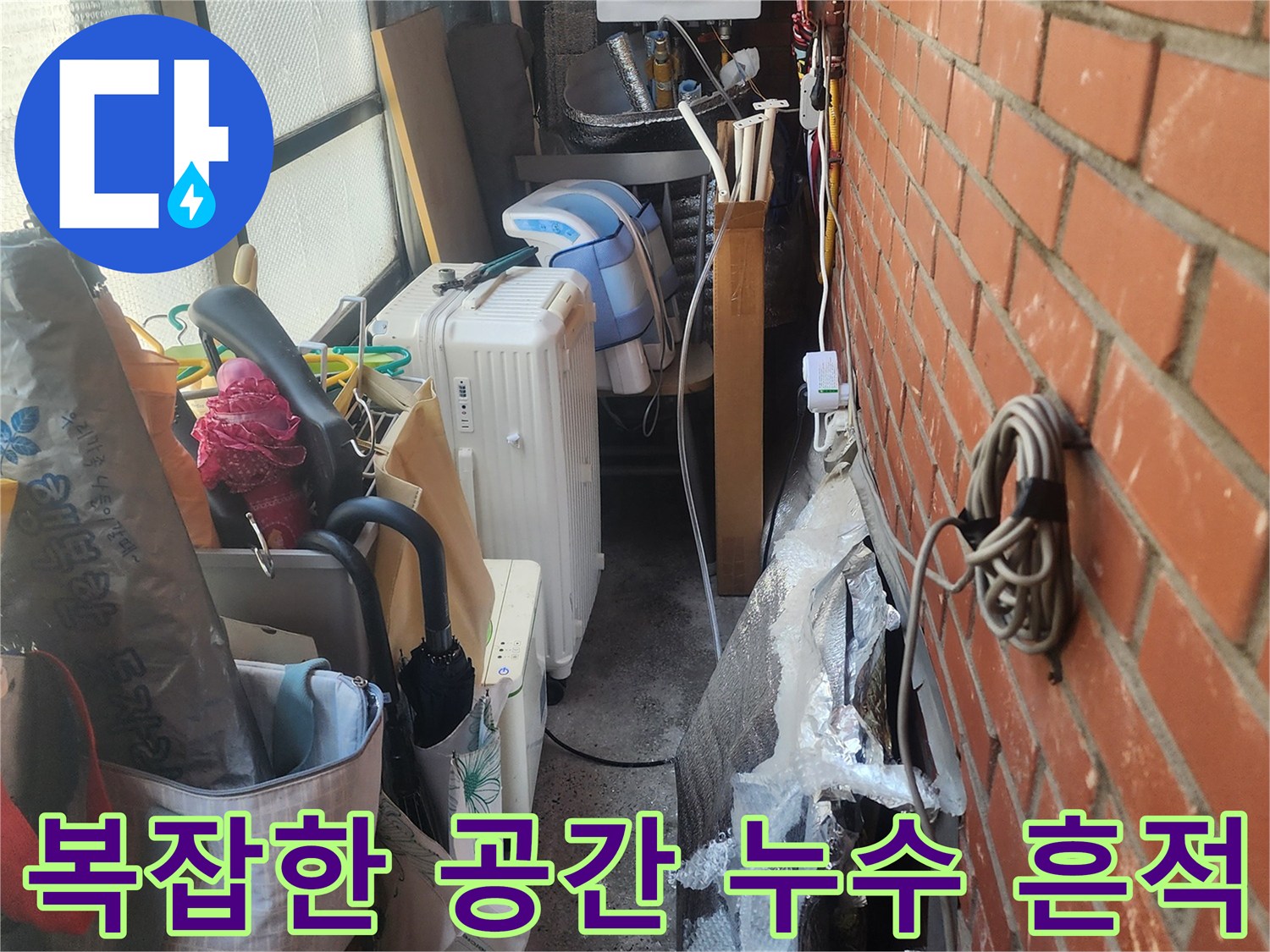 벽돌-벽-아래-복잡하게-얽힌-배관과-생활-용품들-사이에서-발견된-누수-흔적을-보여주는-사진