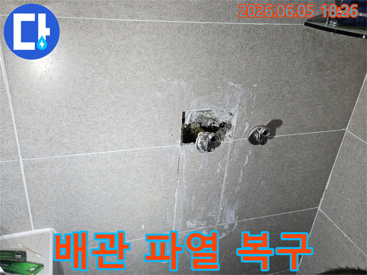 아파트 욕실 벽면 내부에서 파열된 수도 배관을-신속하게 복구하고 있는 전문 기술자의 작업 현장
