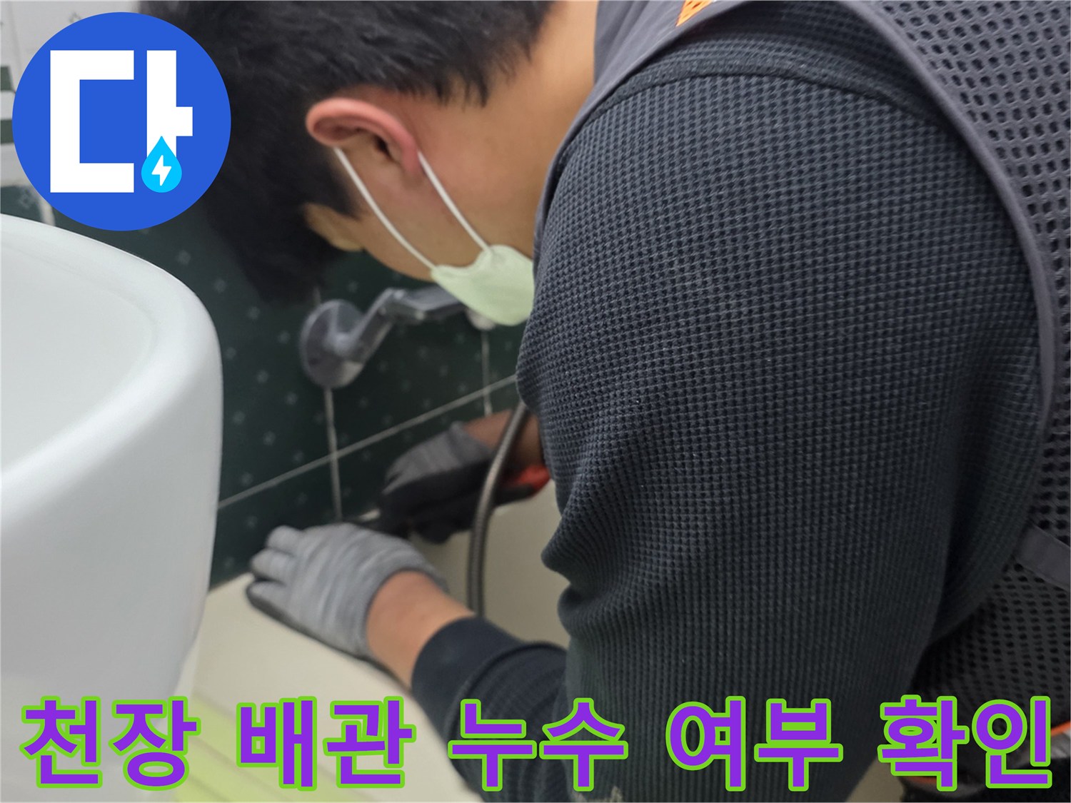 점검구 내부의 배관 연결 부위를 엔지니어가 손전등으로 비추며 검사합니다.