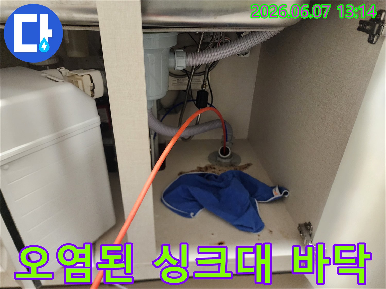 싱크대 하부 배관 주변의 오염물과 젖은 수건이 놓인 모습입니다.