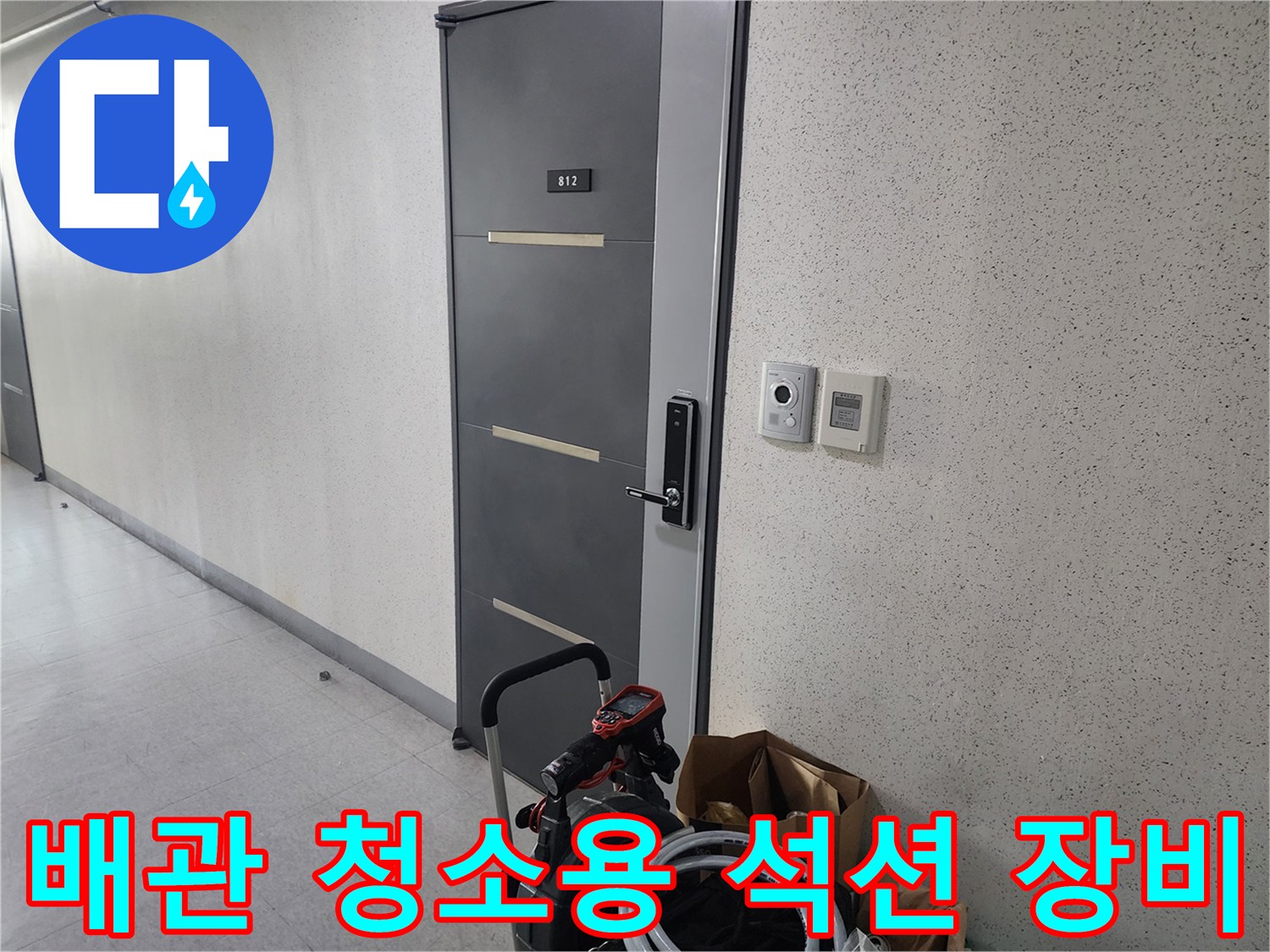문 옆 복도에 놓인 배관 세척 장비와 호스 뭉치
