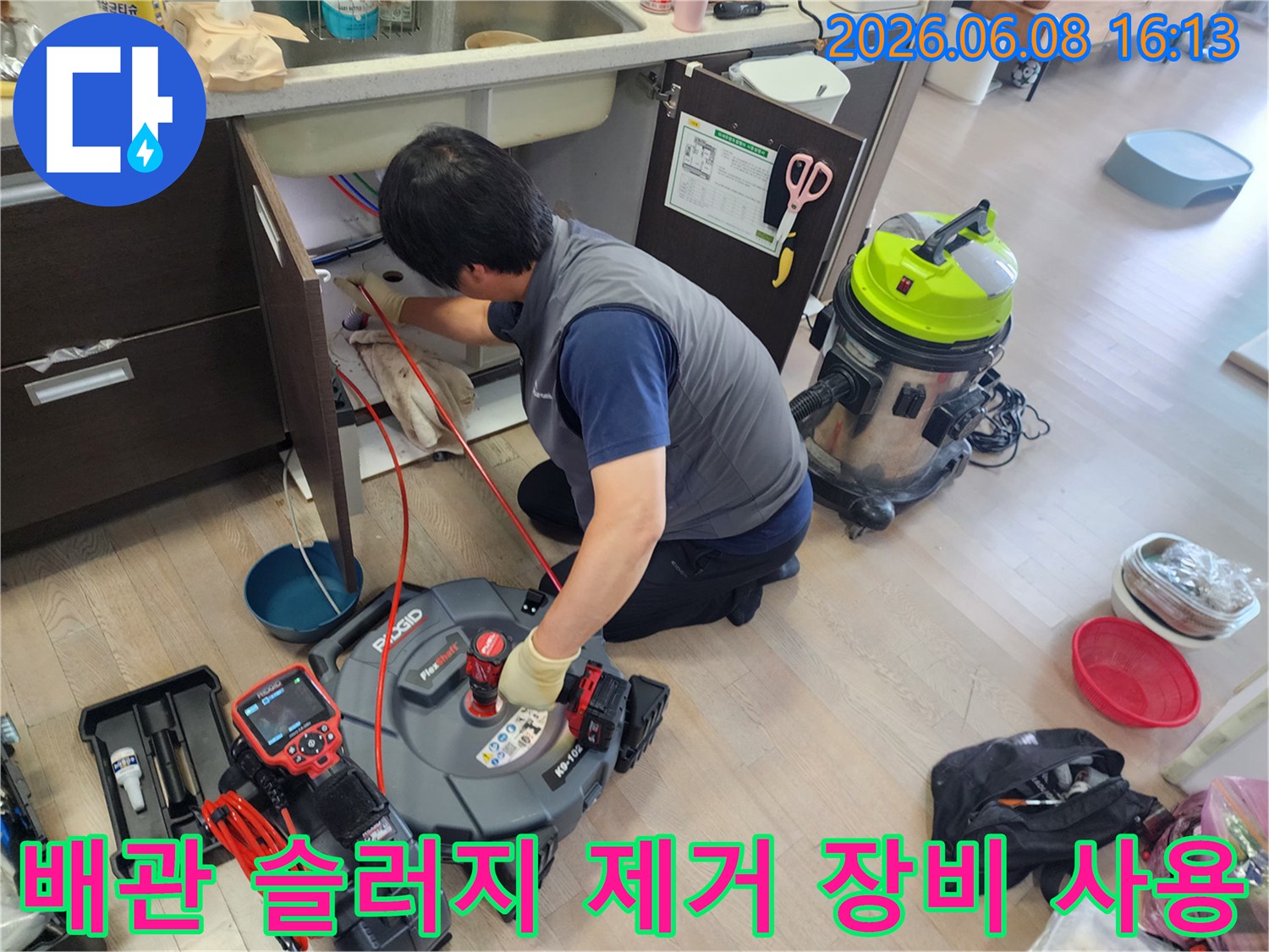 싱크대 하부 배관의 이물질을 제거하기 위해 스케일링 노즐을 투입하는 장면