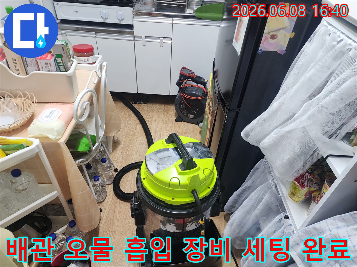 싱크대 아래 배관 청소를 위해 설치된 석션기와 주변 작업 환경입니다.