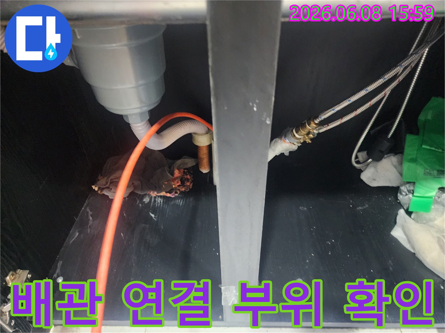주방 싱크대 하부의 호스와 밸브가 복잡하게 얽힌 배관 구조