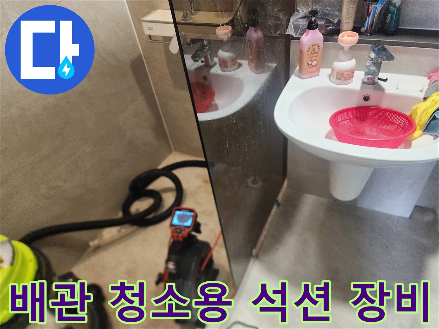 세면대 아래쪽 막힌 부위를 작업하기 위해 놓인 석션기와 호스