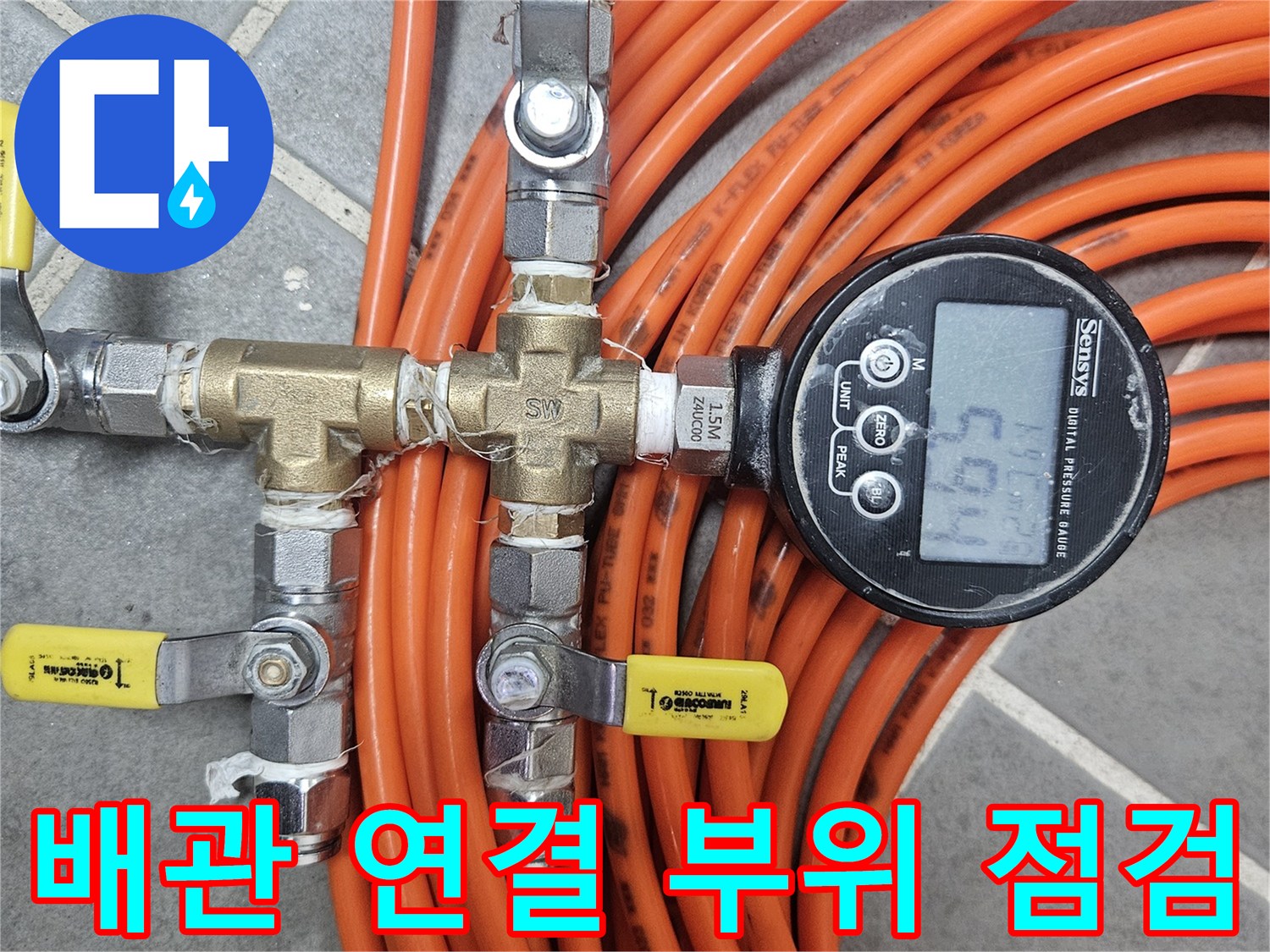 밸브와 호스가 연결된 배관 분기점에 디지털 압력계가 설치되어 있습니다.