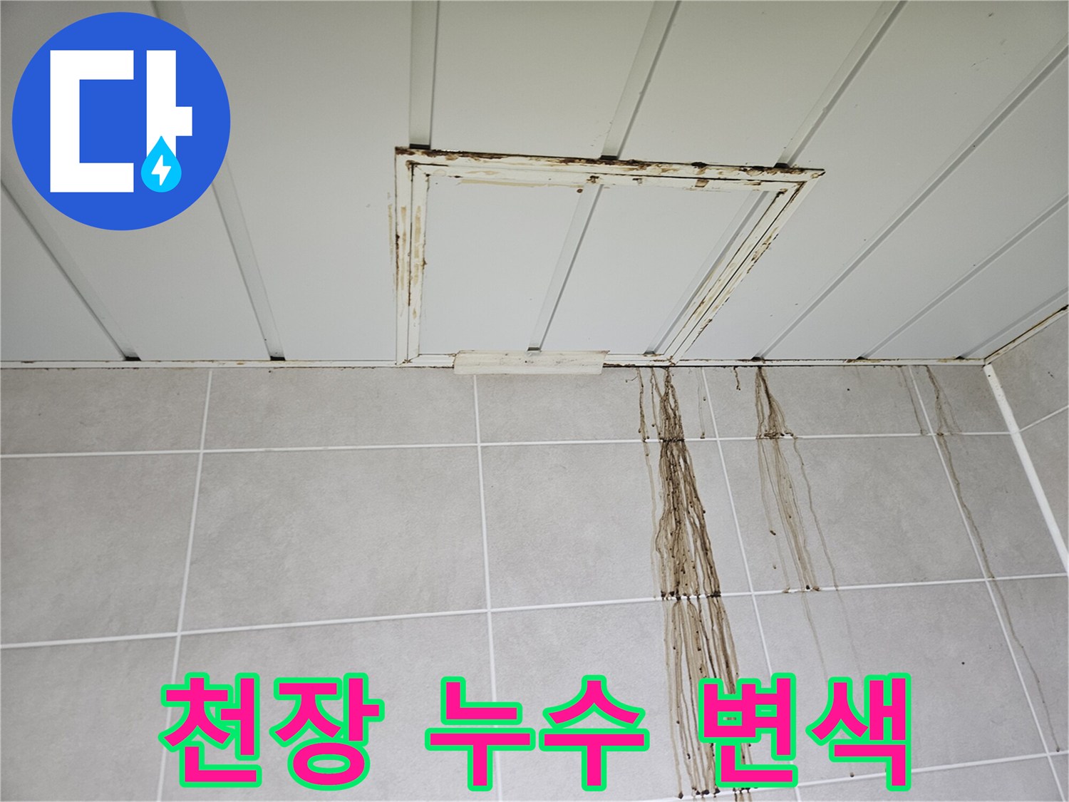 점검구 테두리의 갈색 얼룩과 타일 위로 흐른 누수 자국