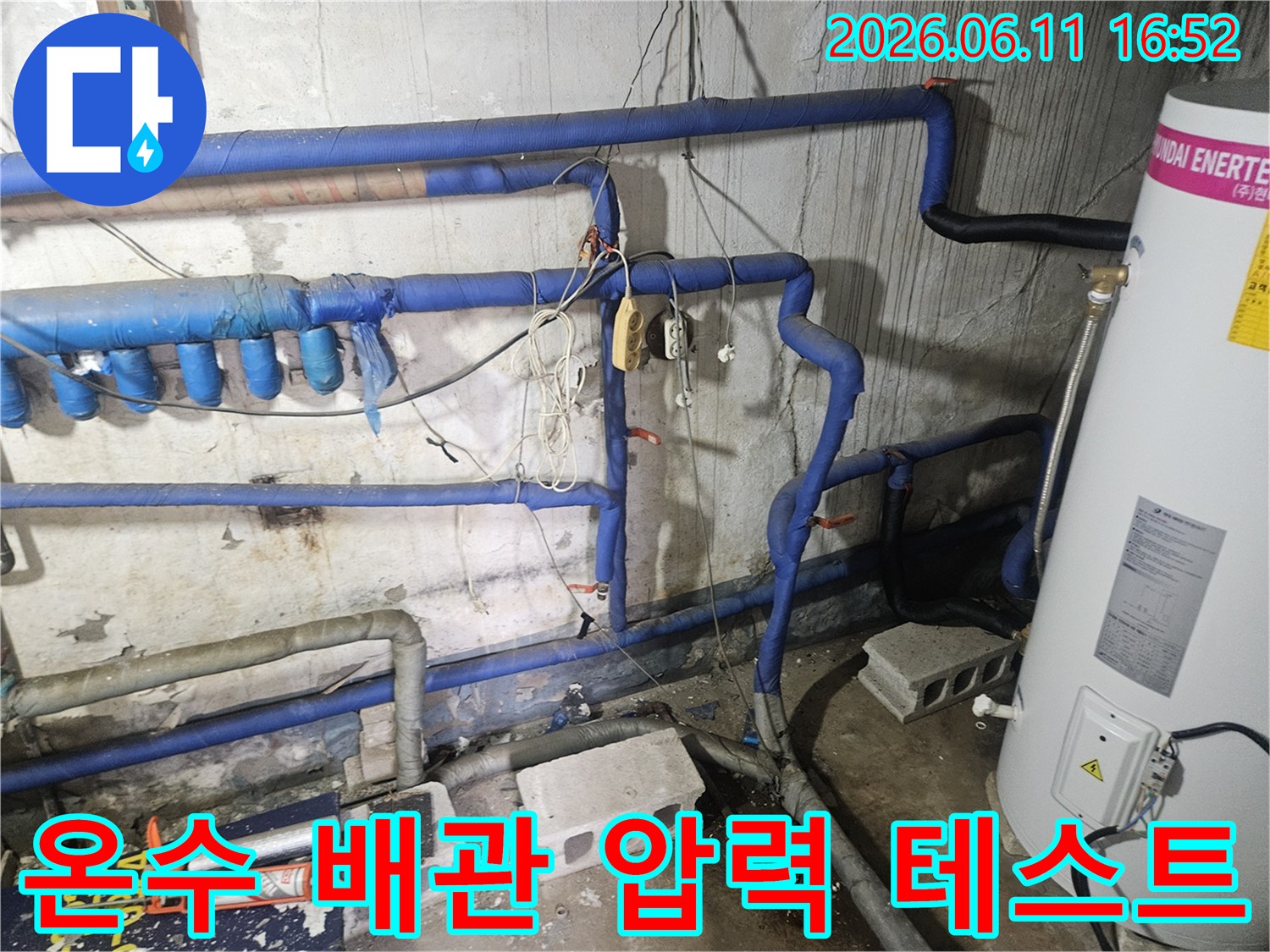 파란색 보온재로 감싸인-온수 배관들이 보이는-압력 테스트를 진행 중인-현장의 모습입니다