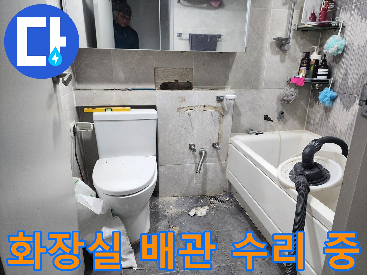이 이미지는-동대문구의 한 아파트 화장실에서-누수 발생 지점의 타일을 제거하고-손상된 배관을 수리하기 위해-작업 중인 현장을 보여줍니다