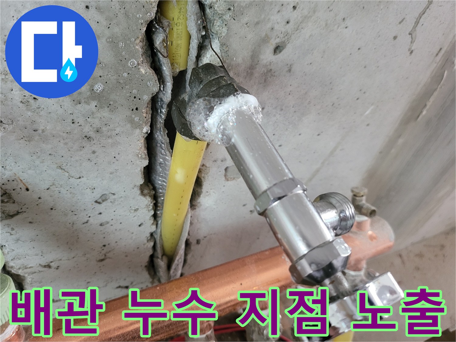 콘크리트 층 아래 드러난 노란색 배관과 금속 분배기 부품