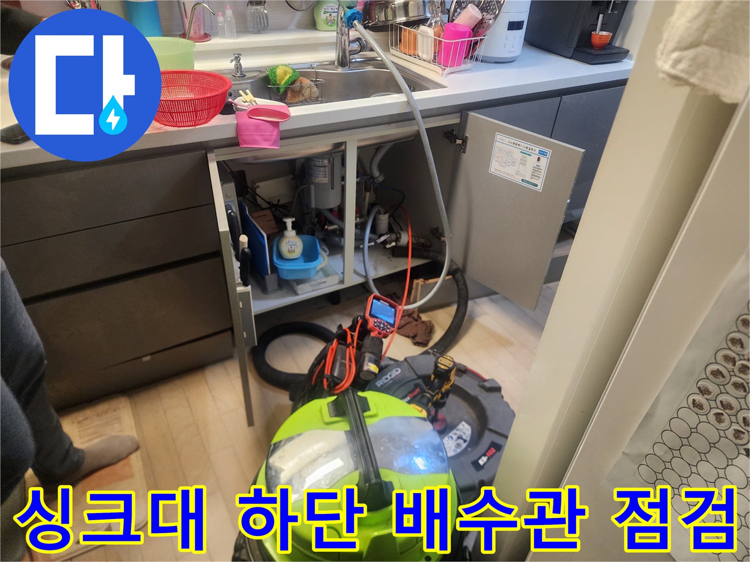 싱크대 아래 배관 주변에 놓인 전문 청소용 석션기 모습입니다.