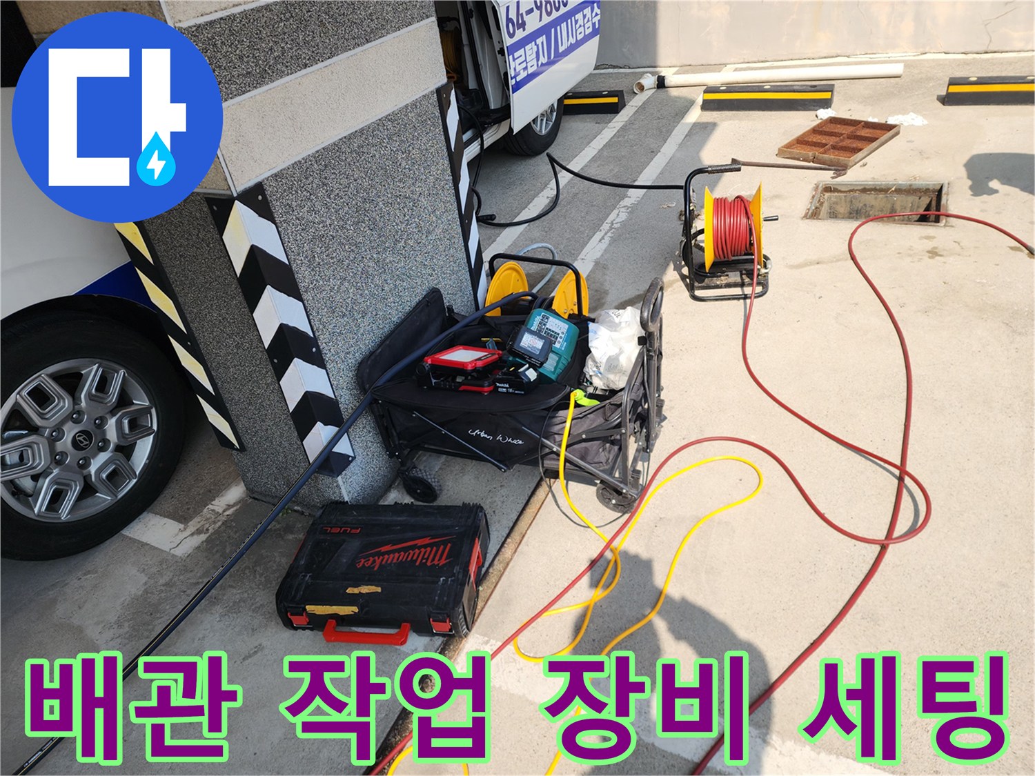 고압 호스와 공구함이 배치된 하수구 작업 현장입니다.