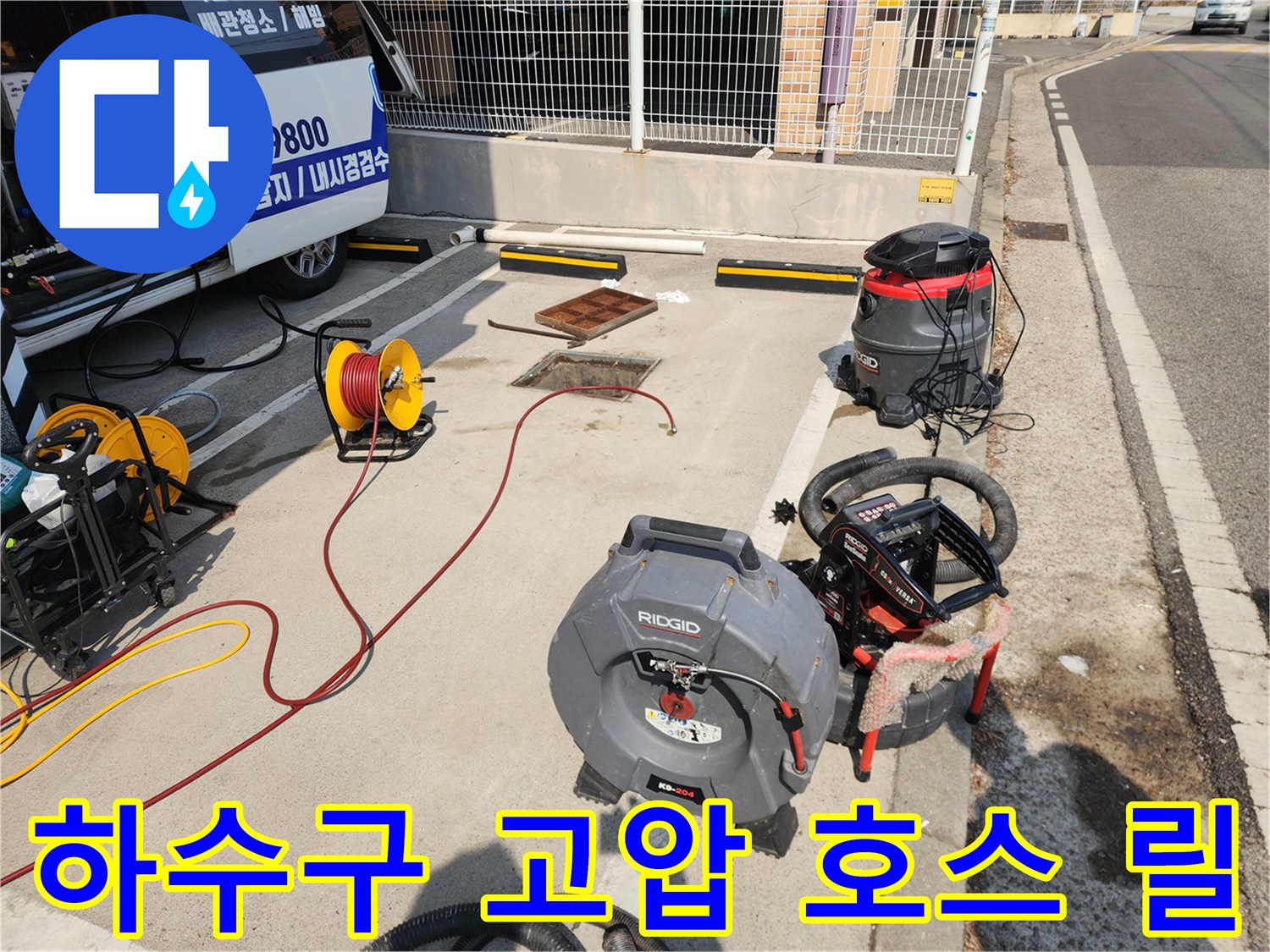 맨홀 근처에 설치된 노란색 호스 릴과 대형 산업용 청소기 장비