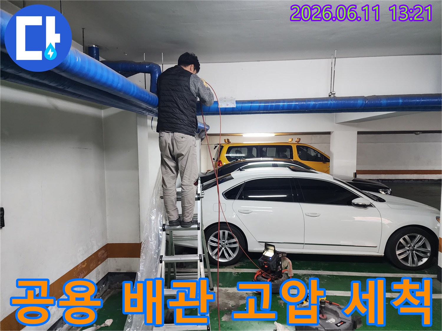 파란색 대형 배관의 막힘을 해결하기 위해 사다리에서 작업 중인 모습