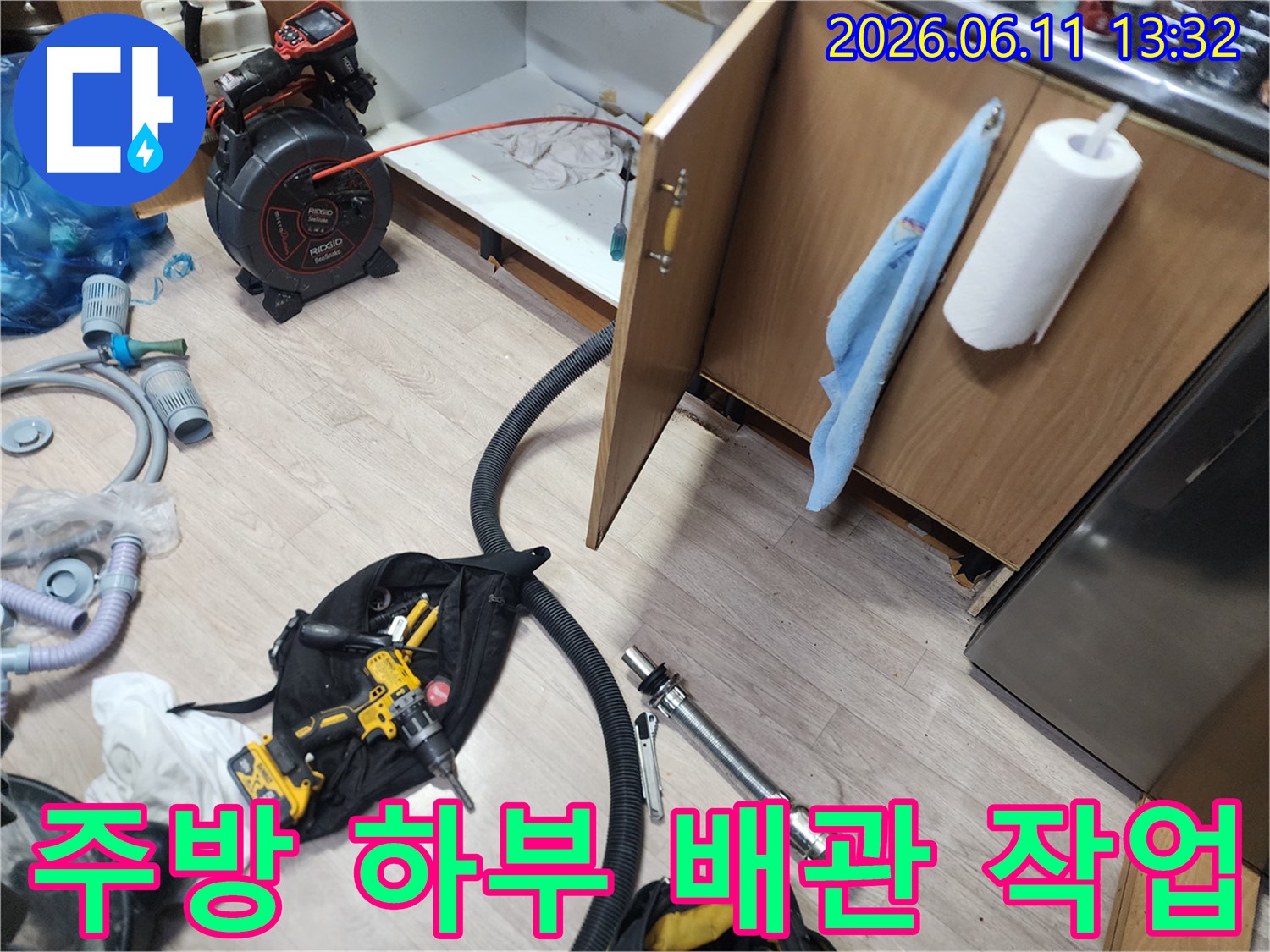 싱크대 하단 하부장 아래에 배치된 배관 점검용 내시경 장비와 공구들입니다.
