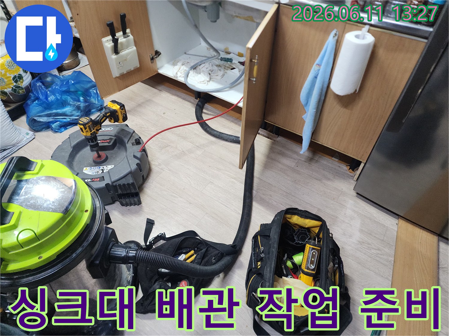 싱크대 하부 배수관 청소를 위해 석션기와 각종 공구를 배치한 현장 사진입니다.