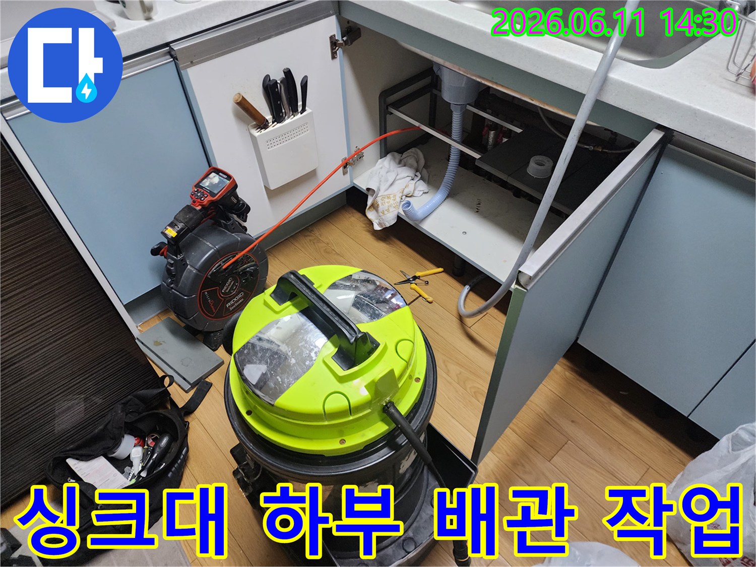 싱크대 밑 공간에-석션기 장비를 배치하여 배수관 청소를 준비하는 모습입니다.
